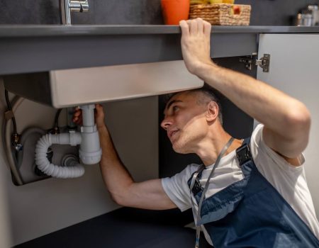 man-carefully-examining-bottom-of-sink-and-pipe-DPQBJ95.jpg